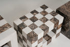 A checkered marble side table or stool with alternating white and dark  veined stone tiles, shown in a close-up studio-style shot.
